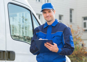 Lieferant in Uniform mit Klemmbrett vor Lieferwagen